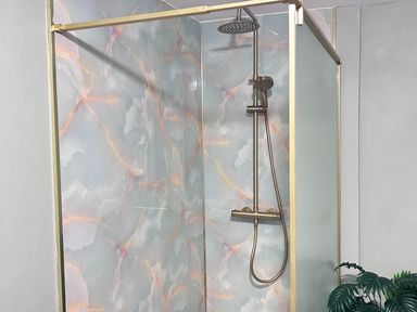 A shower with a glass door and a tiled wall at Downton II in Alnwick