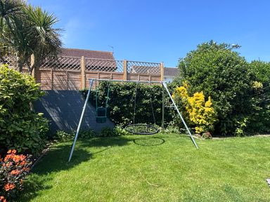 A garden with a swing set and grassy area at 7 Adrian Close Porthcawl