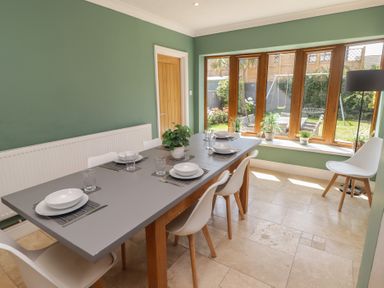 A dining room with a table set for meals at Ty Traeth in Porthcawl