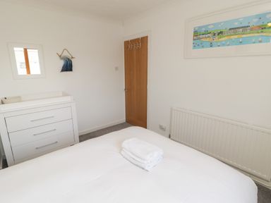 A bedroom with a bed and towel at Ty Traeth in Porthcawl