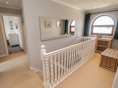 A hallway with a staircase and mirror at Ty Traeth in Porthcawl