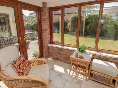 A conservatory with an armchair and a table at Ty Traeth in Porthcawl
