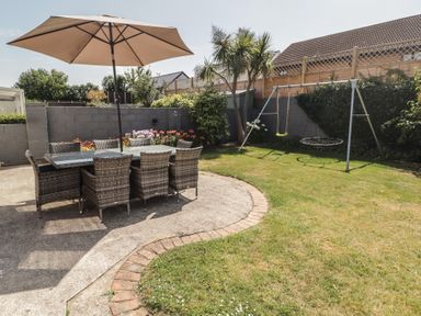 A garden with a dining set and swing set at Ty Traeth in Porthcawl
