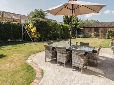 A garden with a dining area featuring a table and chairs at Ty Traeth in Porthcawl
