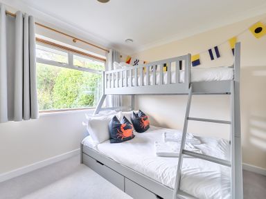 A bedroom with a bunk bed and decorative pillows at Sleeps 9 KingBeds Family Friendly in Pityme near Penmayne