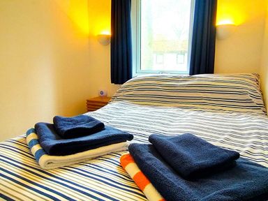 A bedroom with a bed and towels on it at Painters Cottage 2Bed Chalet Free Leisure Passes Near St Ives