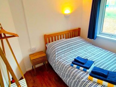 A bedroom with a bed and towels on a nightstand at Painters Cottage 2Bed Chalet Free Leisure Passes Near St Ives