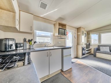 A kitchen with appliances and seating area at Sleeps 8 Communal Spa Access Parking Rhyl