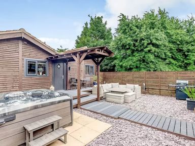 A garden with a wooden cabin and hot tub at Luxury 2 bedroom Lodge in rural lincolnshire