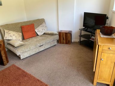 A living room with a sofa and television at Bungalow Sleeps 2 Parking in Newquay