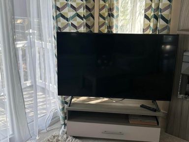 A television on a stand with a remote control in the living room at Caravan in Holcot Sleeps 6 Max 6 people Max 4 adults per booking Pet Friendly Holcot near Moulton