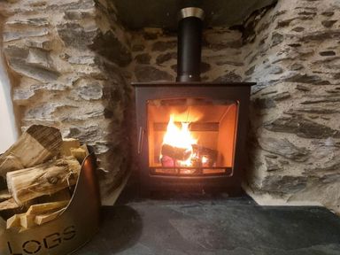 A wood stove with flames and logs in a living room at Looe Cottage Seaside views log fire sleeps 4 Looe