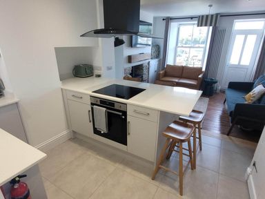 A kitchen with an oven and bar stools at Looe Cottage Seaside views log fire sleeps 4 in Looe