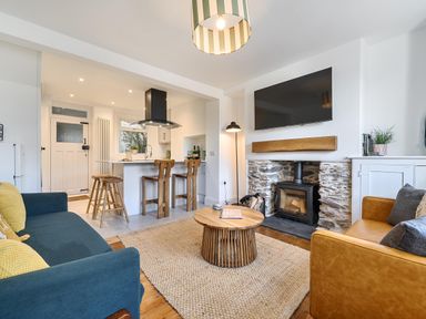 A living room with a sofa, armchair, coffee table, and television at Looe Cottage Seaside views log fire sleeps 4 Looe