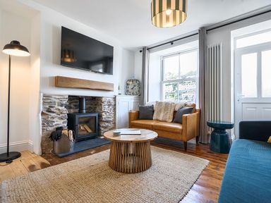 A living room with a sofa, coffee table, and fireplace at Looe Cottage Seaside views log fire sleeps 4 in Looe