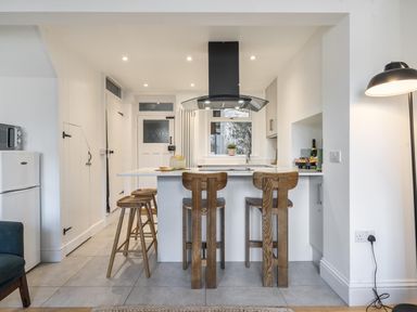 A kitchen with bar stools and countertop at Looe Cottage Seaside views log fire sleeps 4, Looe