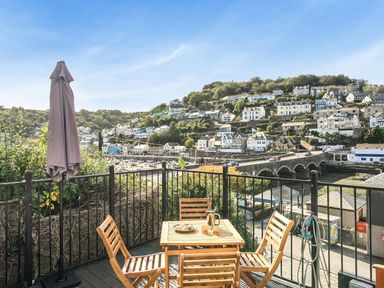 An outdoor patio with a table and chairs overlooking a coastal town at Looe Cottage Seaside views log fire sleeps 4 Looe