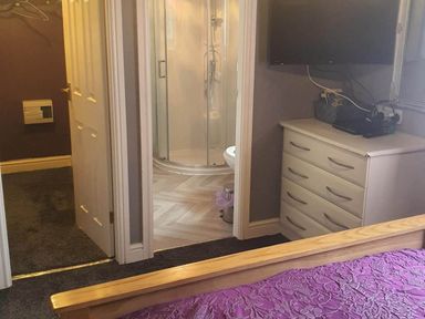 A bedroom with a dresser and a bathroom featuring a shower at Fleetwood