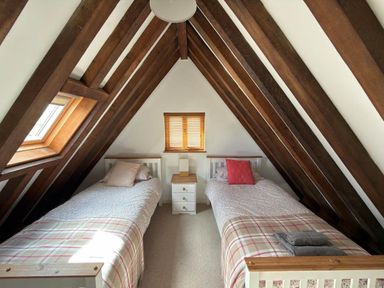 A bedroom with two single beds and wooden beams at Tremail near Camelford