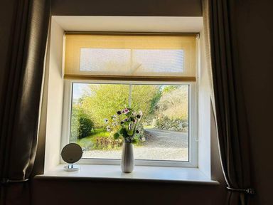 A window with a flower vase and a mirror at a property in Nebo near Penygroes