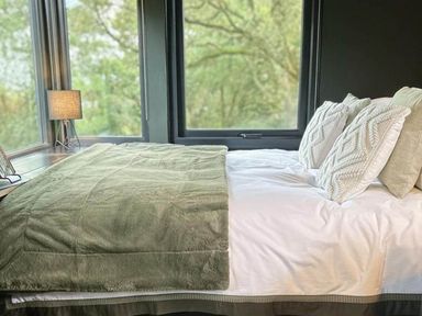 A bed with pillows and a blanket near a window at The Old Barn in Newton Abbot