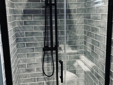A shower with tiles and a glass door at The Old Barn in Newton Abbot