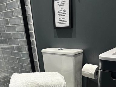 A bathroom with a toilet and a sign at The Old Barn in Newton Abbot