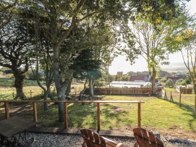 A garden area with trees and outdoor furniture at Owls Roost in Robin Hood’s Bay
