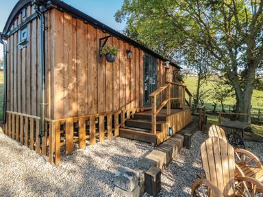 A wooden cabin with steps and outdoor seating at Owls Roost in Robin Hood’s Bay