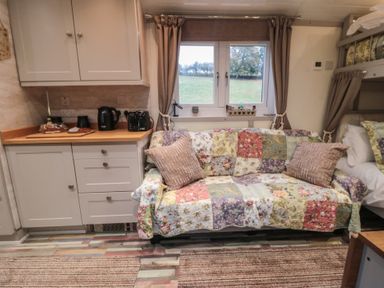 A living room with a sofa and kitchenette at Owls Roost in Robin Hood’s Bay