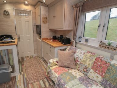 A kitchen with appliances and a sofa at Owls Roost Robin Hood’s Bay