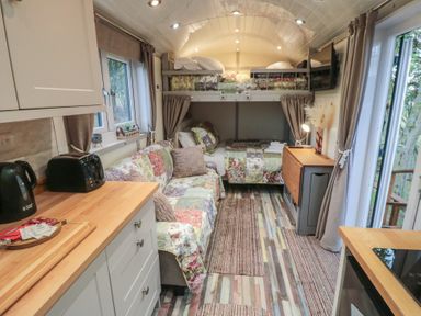 A tiny house interior with a sofa and beds at Owls Roost in Robin Hood’s Bay