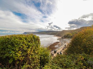 A coastal view with a beach and pathway at Owls Roost in Robin Hood’s Bay