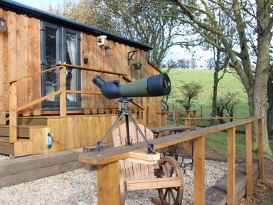 A telescope on a deck in front of a wooden cabin at Owls Roost in Robin Hood’s Bay