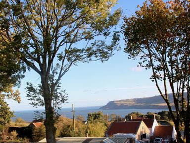 A view of the sea and hills with trees and houses at Owls Roost in Robin Hood’s Bay