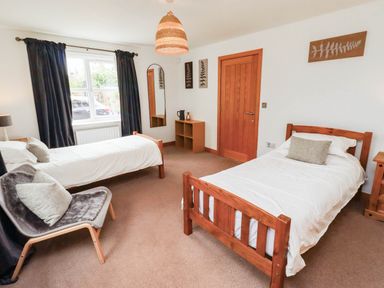 A bedroom with two beds and a chair at Alma House in Seahouses