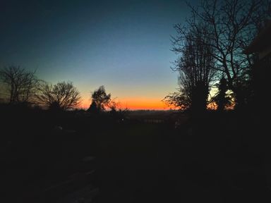 A sunset view with trees in the foreground at Fables Cottage Otley, Suffolk