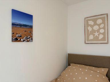 A bedroom with a beach photo and shell artwork at 7 Cwrt Y Cadno in Llantwit Major