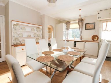 A dining room with a glass table and white chairs at Westgate Willows Nafferton