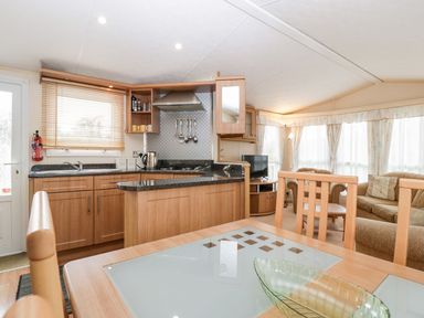 A living room and kitchen area with a dining table and chairs at The Hideaway in Portesham