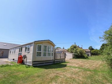 A mobile home with a deck and surrounding grass at The Hideaway in Portesham