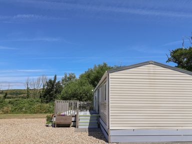 A mobile home with a deck and stairs at The Hideaway in Portesham