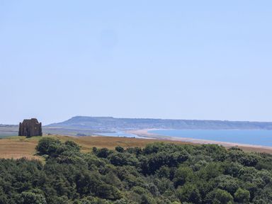 A view of a building on hills overlooking the ocean at The Hideaway in Portesham