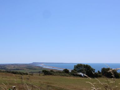 A view of the sea and beach from a grassy area at The Hideaway in Portesham