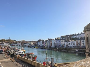 A harbor with boats and colorful buildings at The Hideaway in Portesham