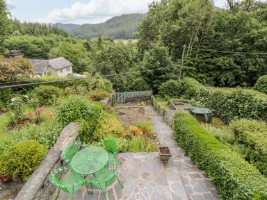 A garden with a table and chairs overlooking greenery at Awelfryn Betws-y-Coed