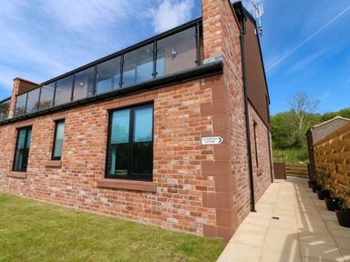 An exterior view of a brick house with a balcony at Silver Birch Cottage in Frizington