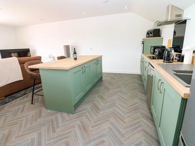 A kitchen with a green island and appliances at Silver Birch Cottage in Frizington