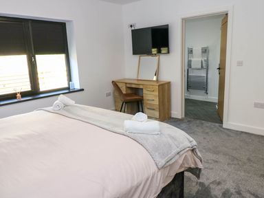 A bedroom with a bed and a desk at Silver Birch Cottage in Frizington