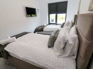 A bedroom with two beds and a television at Silver Birch Cottage in Frizington